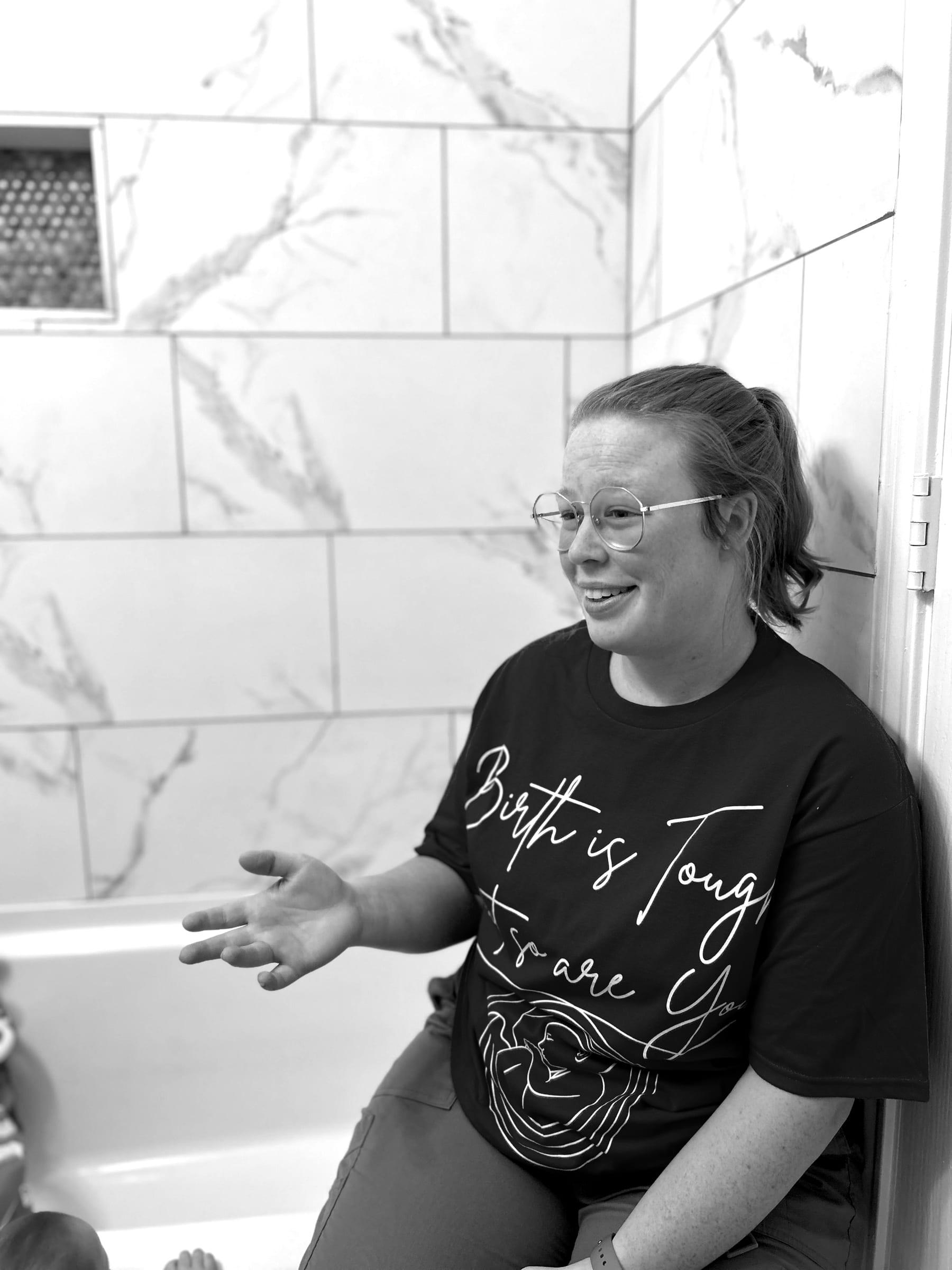 Mackenzie mid-conversation, smiling, in a 'Birth is Tough' shirt
