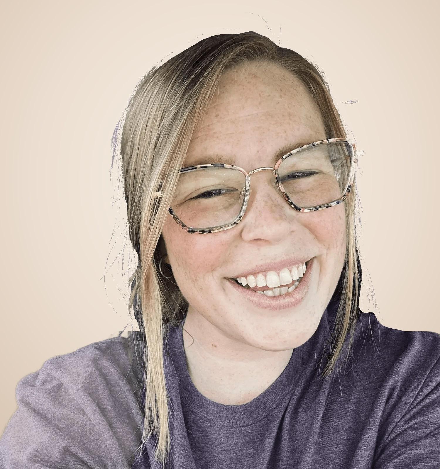 Mackenzie Pineda smiling warmly, wearing glasses and a purple t-shirt