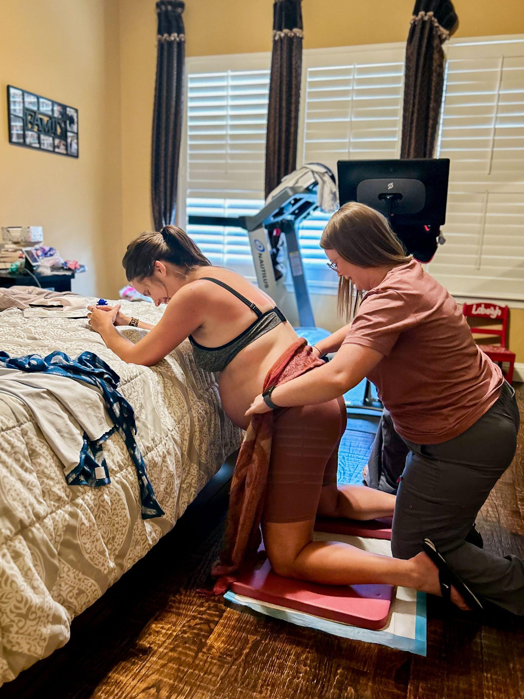 Mackenzie using a rebozo to support a laboring mother kneeling at the edge of a bed