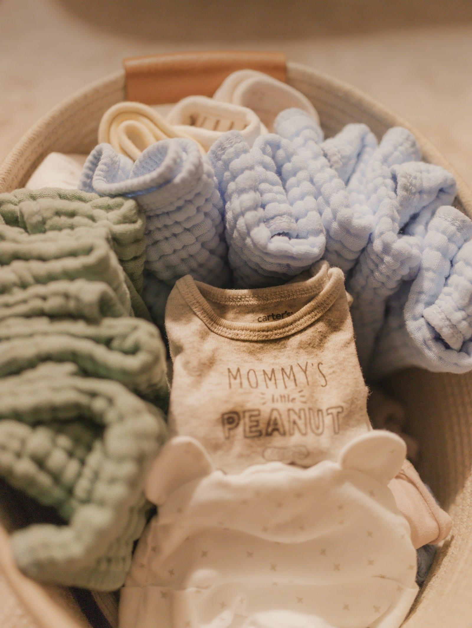 Freshly folded baby clothes in a woven basket