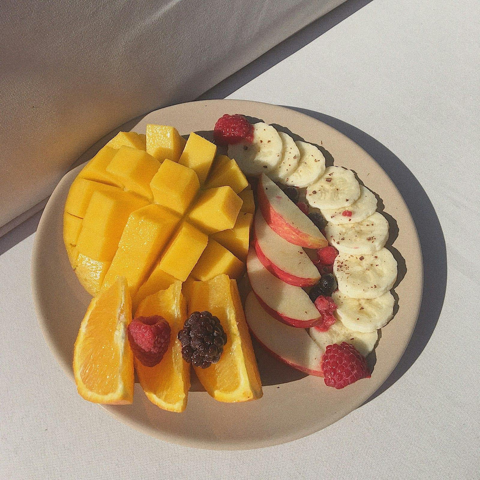 A plate of fresh-cut fruit, ready to eat with one hand